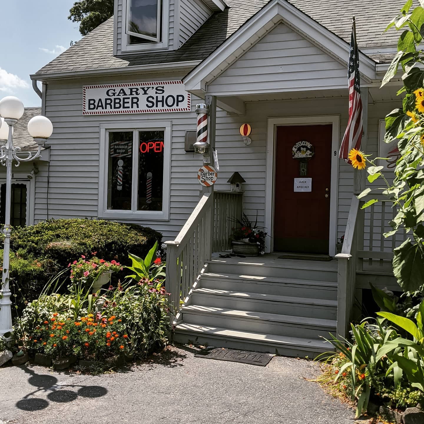 The storefront of Gary's Barber Shop in Brookfield, CT, with a lit barber pole and OPEN sign
